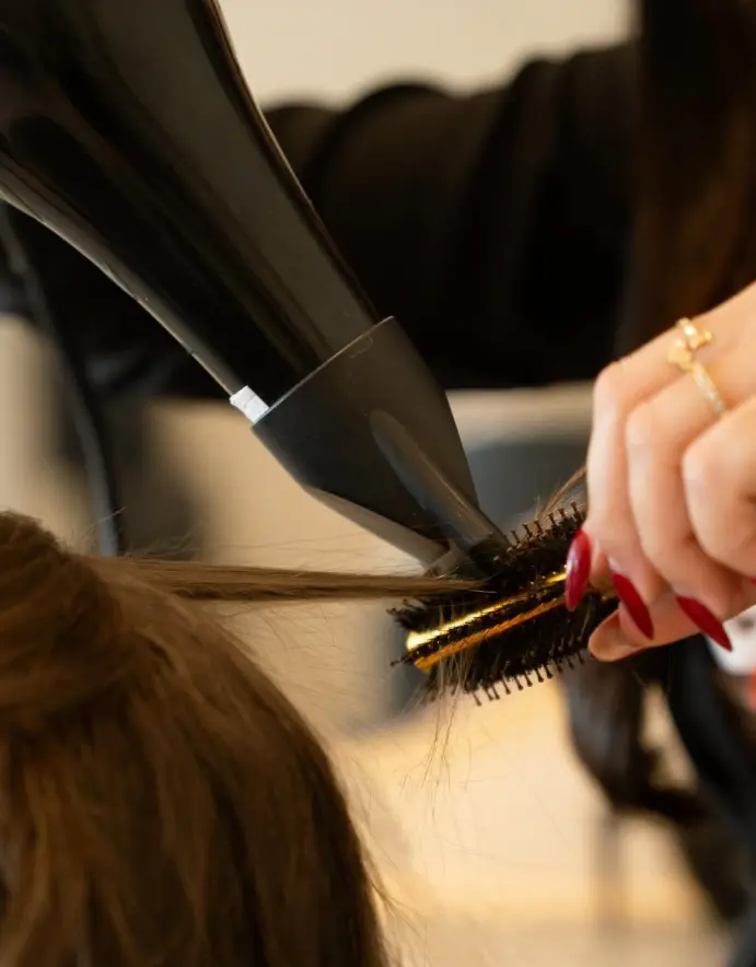 Profissional realizando uma escova em cabelo feminino